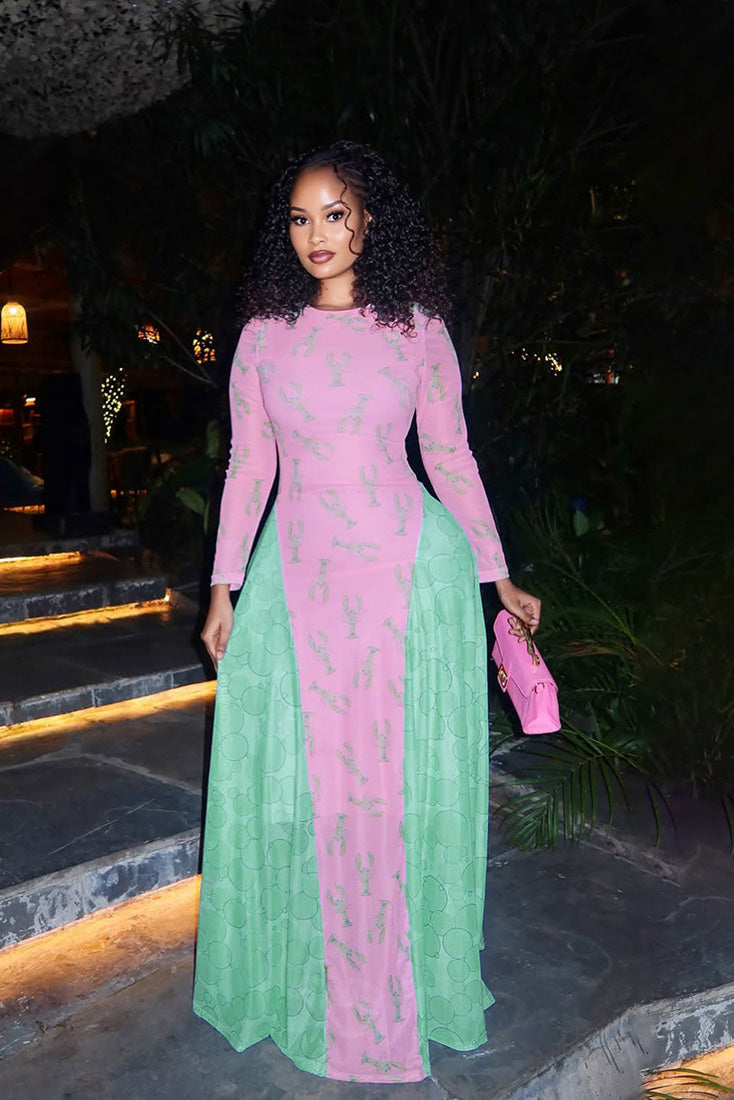 Woman in pink lobster print mesh dress with green flowing skirt and a green purse.