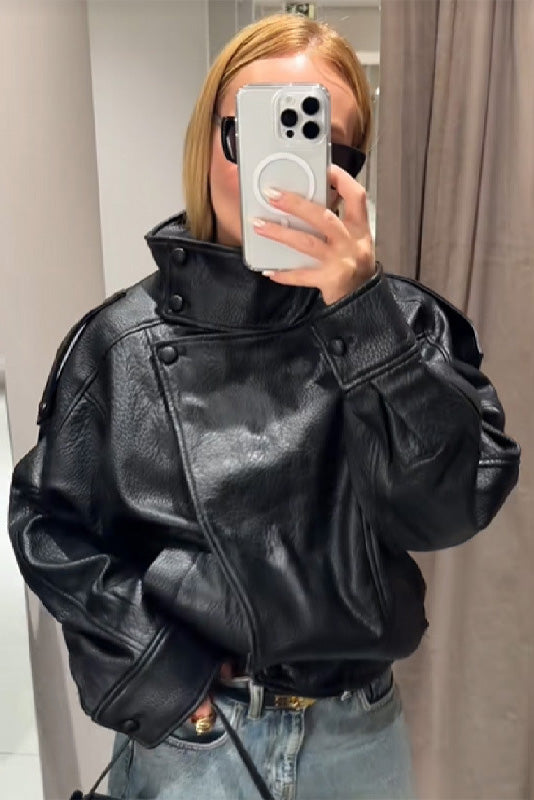 Black - A woman taking a mirror selfie wearing an oversized, black pebbled faux leather jacket with a high snap-button collar, dropped shoulders, and a cropped fit.