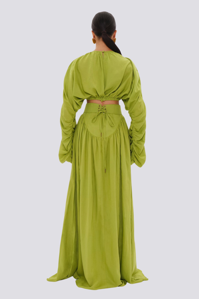 Green - Full-length studio shot of a woman wearing a vibrant lime green two-piece set, featuring a long-sleeved cropped top with ruched arms and matching high-waisted, wide-leg trousers.