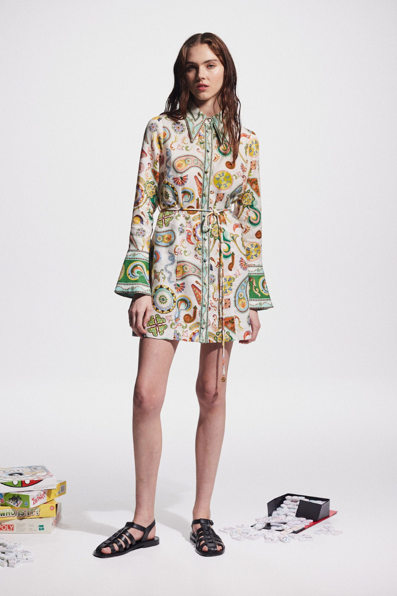 Multicolor - Full-length studio shot of a female model wearing a long-sleeved, collared mini shirt dress featuring a colourful paisley print, cinched at the waist with a tie-belt.