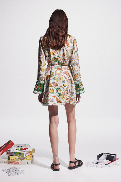 Multicolor - Full-length studio shot of a female model wearing a long-sleeved, collared mini shirt dress featuring a colourful paisley print, cinched at the waist with a tie-belt.