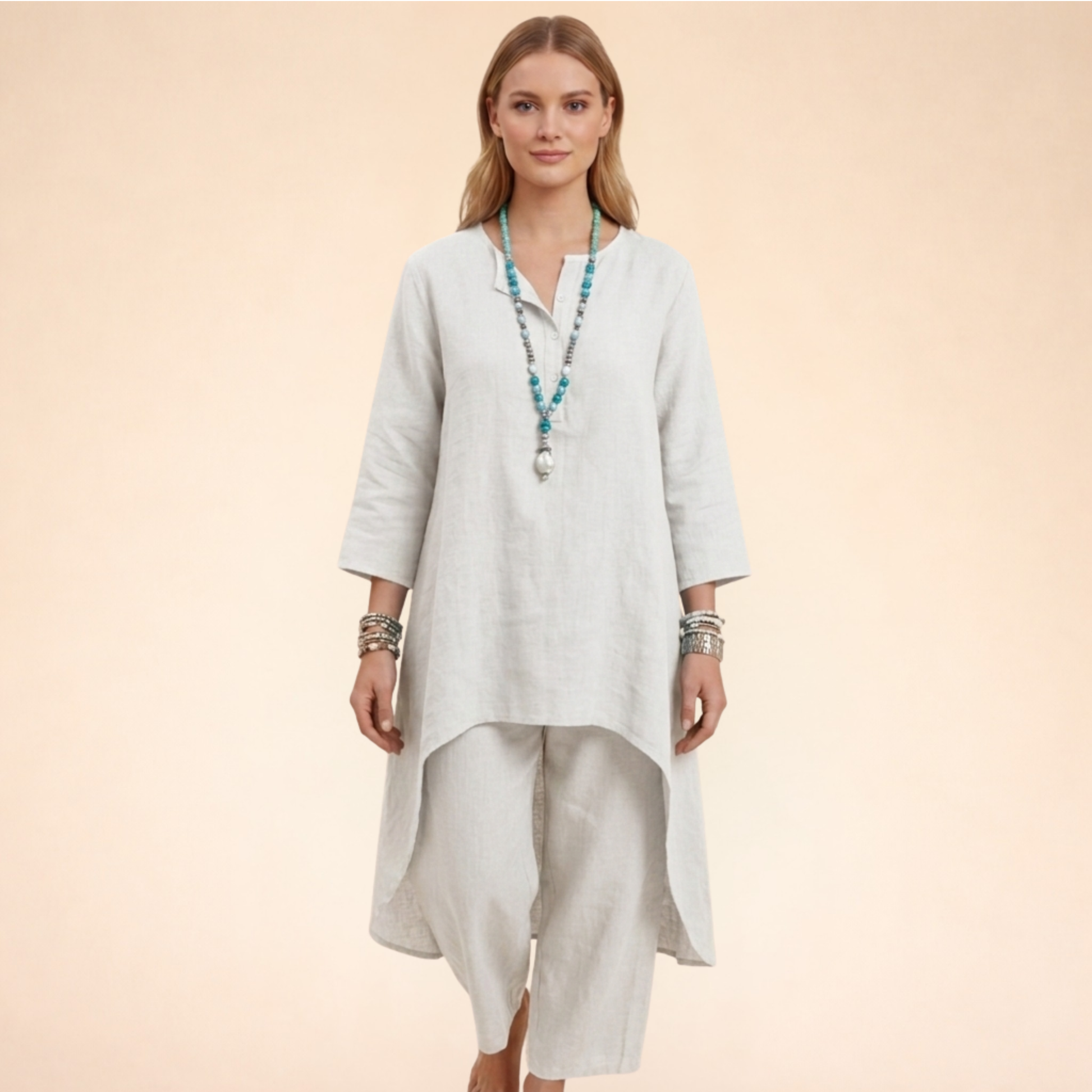 Weiß - A woman modelling a light-coloured, relaxed-fit resort tunic top featuring a split neckline, three-quarter sleeves, and a dramatic high-low hemline.