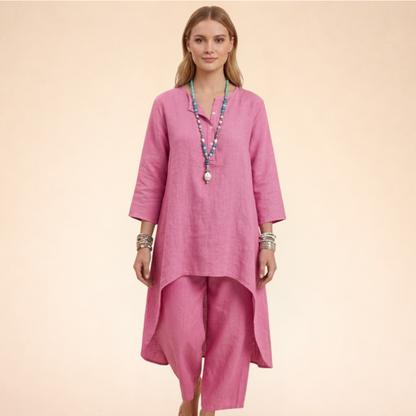 Rosa - A woman modelling a light-coloured, relaxed-fit resort tunic top featuring a split neckline, three-quarter sleeves, and a dramatic high-low hemline.
