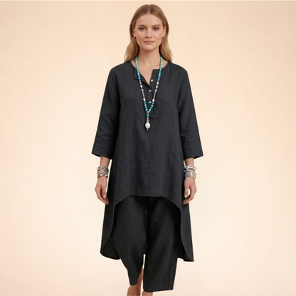 Rosa - A woman modelling a light-coloured, relaxed-fit resort tunic top featuring a split neckline, three-quarter sleeves, and a dramatic high-low hemline.