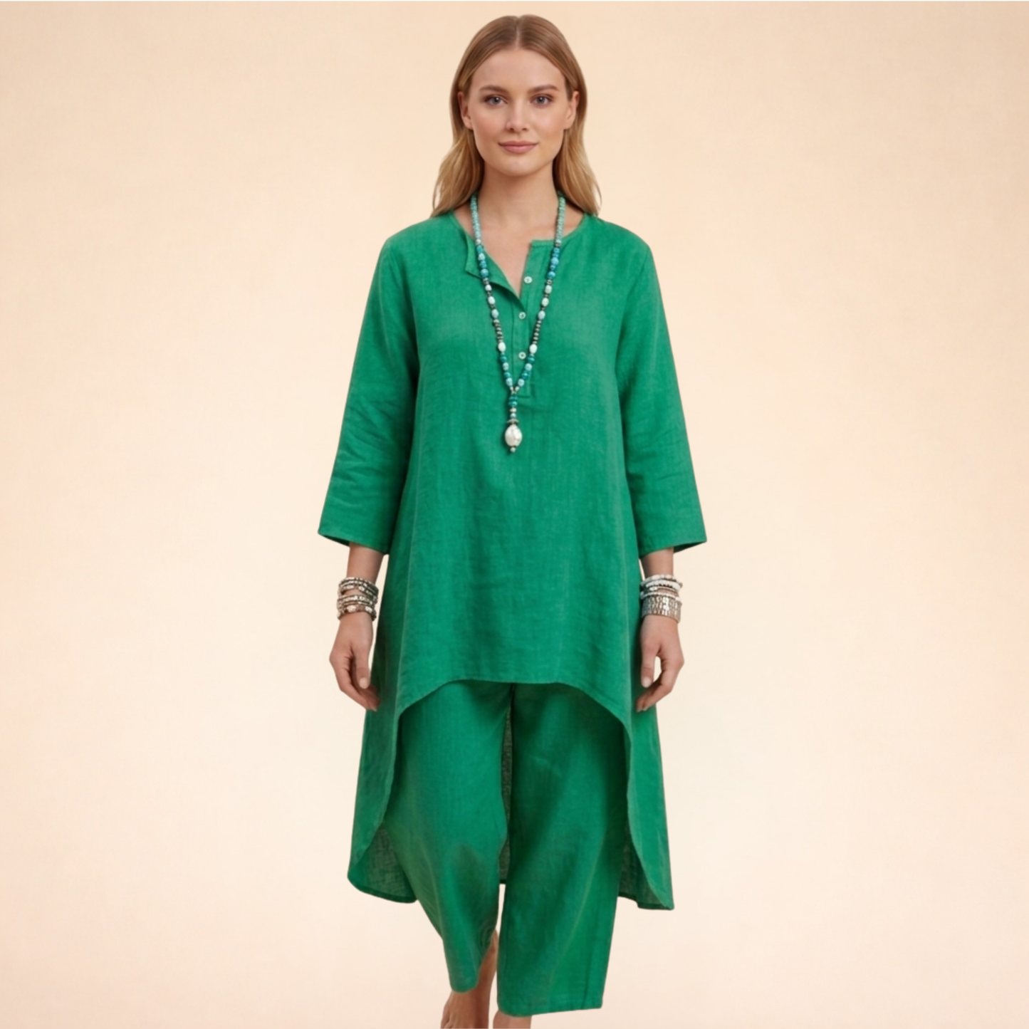 Grün - A woman modelling a light-coloured, relaxed-fit resort tunic top featuring a split neckline, three-quarter sleeves, and a dramatic high-low hemline.