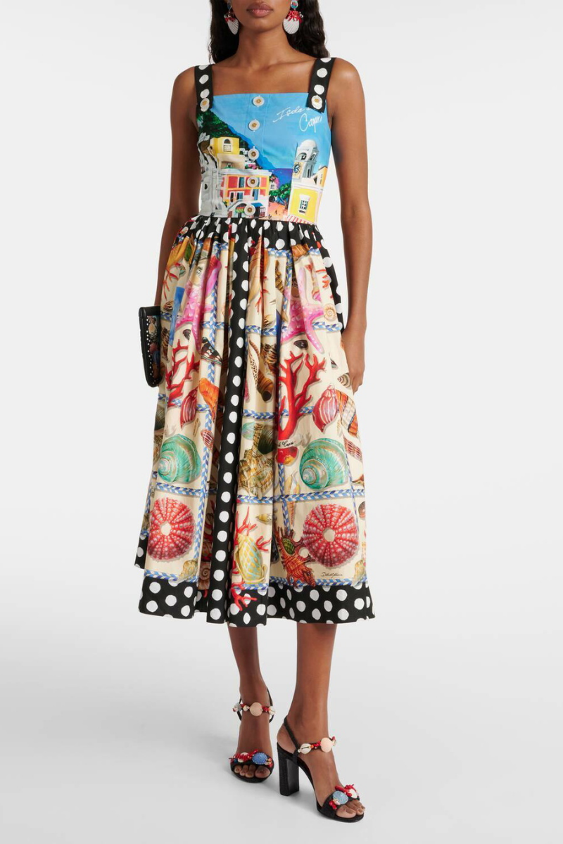 Full-length view of a woman wearing a mixed-print midi dress with a scenic-print square-neck bodice, polka dot straps, and a full A-line skirt featuring seashell and polka dot panels.