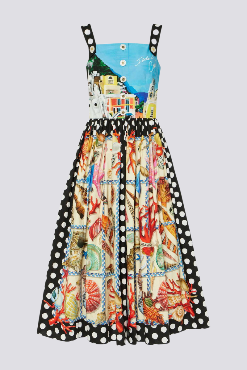 Full-length view of a woman wearing a mixed-print midi dress with a scenic-print square-neck bodice, polka dot straps, and a full A-line skirt featuring seashell and polka dot panels.