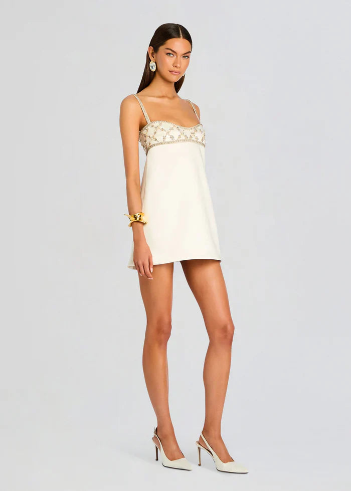 Women's white evening mini dress featuring a structured shift silhouette, slender straps, and a heavily embellished bodice with a sequin lattice pattern.