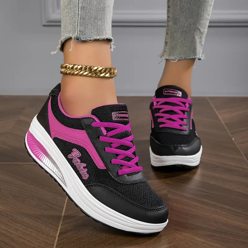 Schwarz mit Lila - Close-up of a woman's lower legs wearing light wash, slim-fit denim pants featuring a frayed raw hem at the ankle, styled with black platform sneakers and a chunky gold anklet.