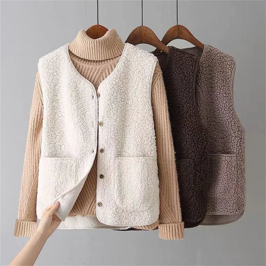 Beige - Three women's faux shearling vests in cream, dark brown, and taupe hanging on wooden hangers, featuring a V-neck, button-front closure, and large patch pockets.
