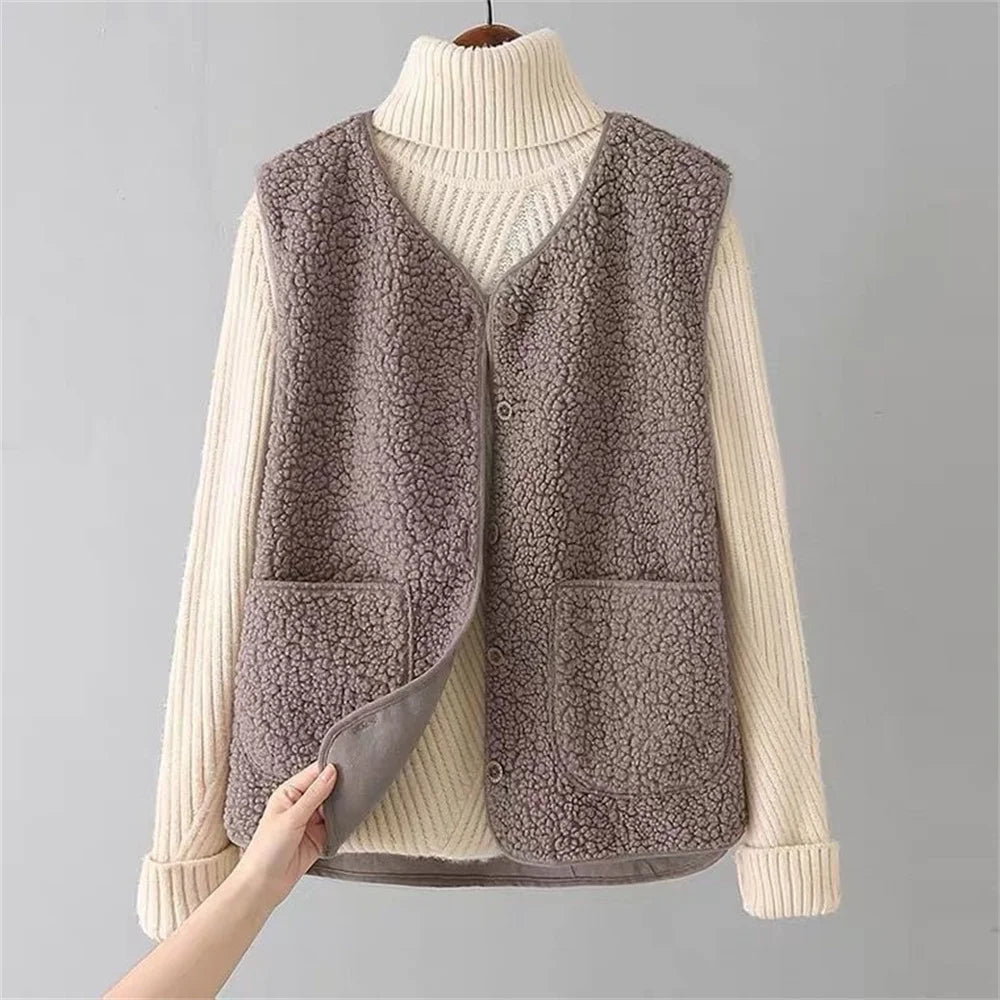Brown - Three women's faux shearling vests in cream, dark brown, and taupe hanging on wooden hangers, featuring a V-neck, button-front closure, and large patch pockets.