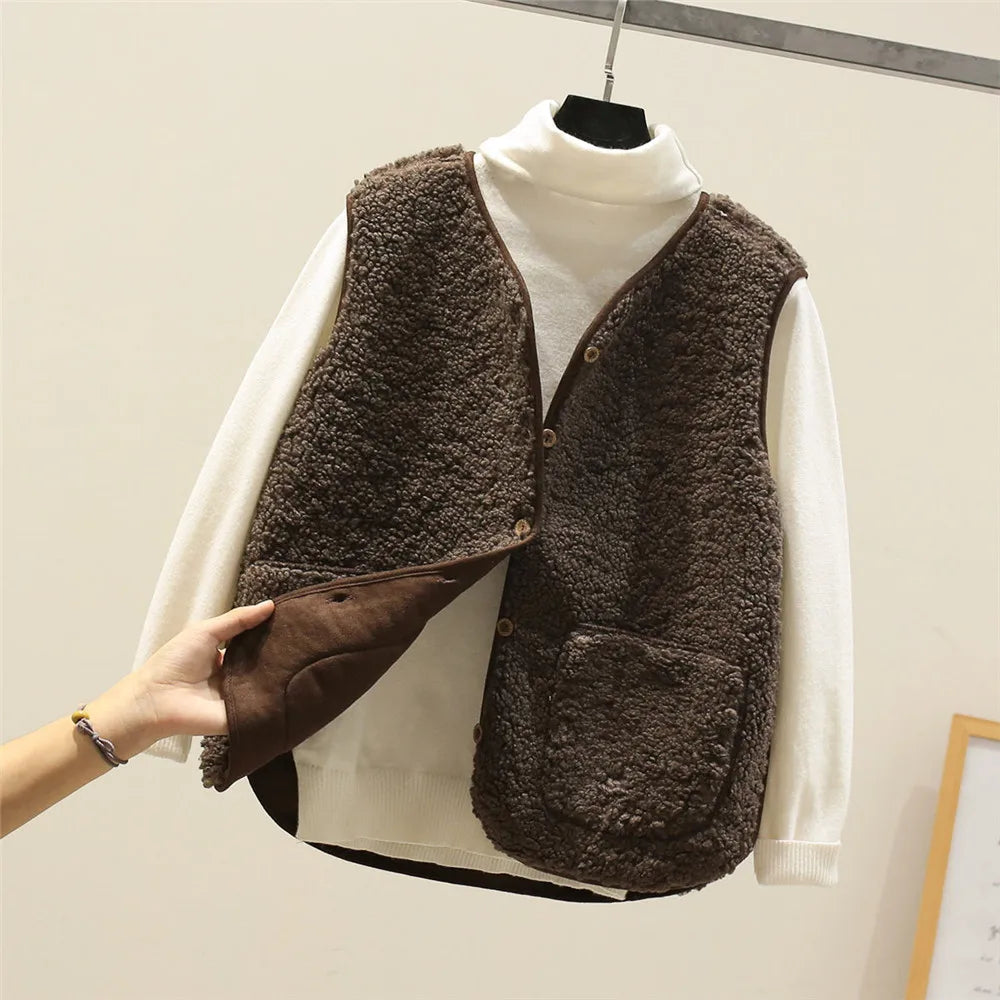 Khaki - Three women's faux shearling vests in cream, dark brown, and taupe hanging on wooden hangers, featuring a V-neck, button-front closure, and large patch pockets.