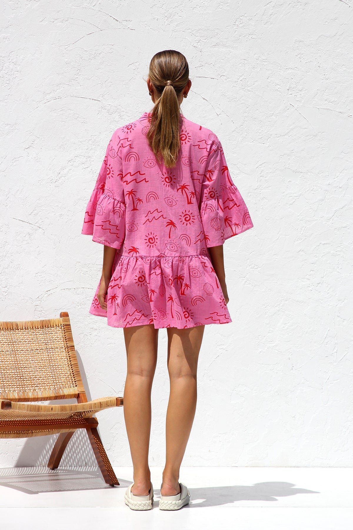 Woman in pink linen mini dress with red print