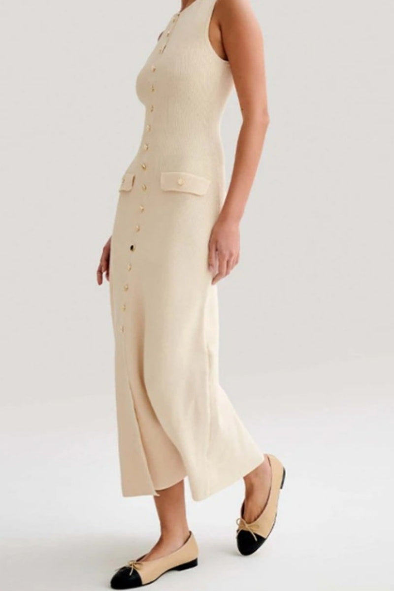 A woman wears a sleeveless, cream-colored ribbed knit midi dress featuring a high neckline, a full front placket of gold-tone buttons, and two small flap pockets at the hips.