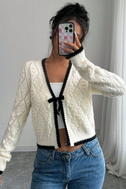 Woman in cream cable knit cardigan and flared jeans taking a selfie