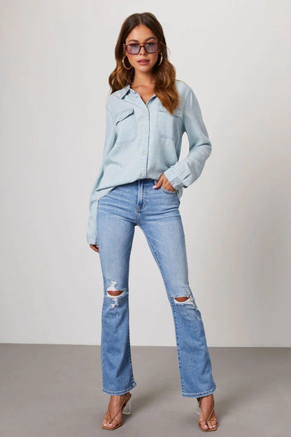 Light Blue - Women's light blue denim button-down shirt featuring a point collar, dual chest flap pockets, and rolled sleeves secured with button tabs, styled casually.