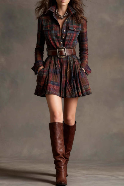A woman models a long-sleeve, collared mini shirtdress in a multicolor plaid pattern. The dress is cinched with a wide brown belt and features a full, flared skirt, styled with tall brown boots against a grey studio background.
