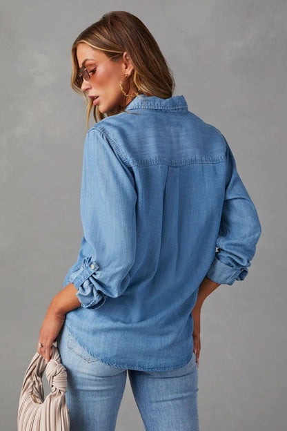 Blue - Women's light blue denim button-down shirt featuring a point collar, dual chest flap pockets, and rolled sleeves secured with button tabs, styled casually.