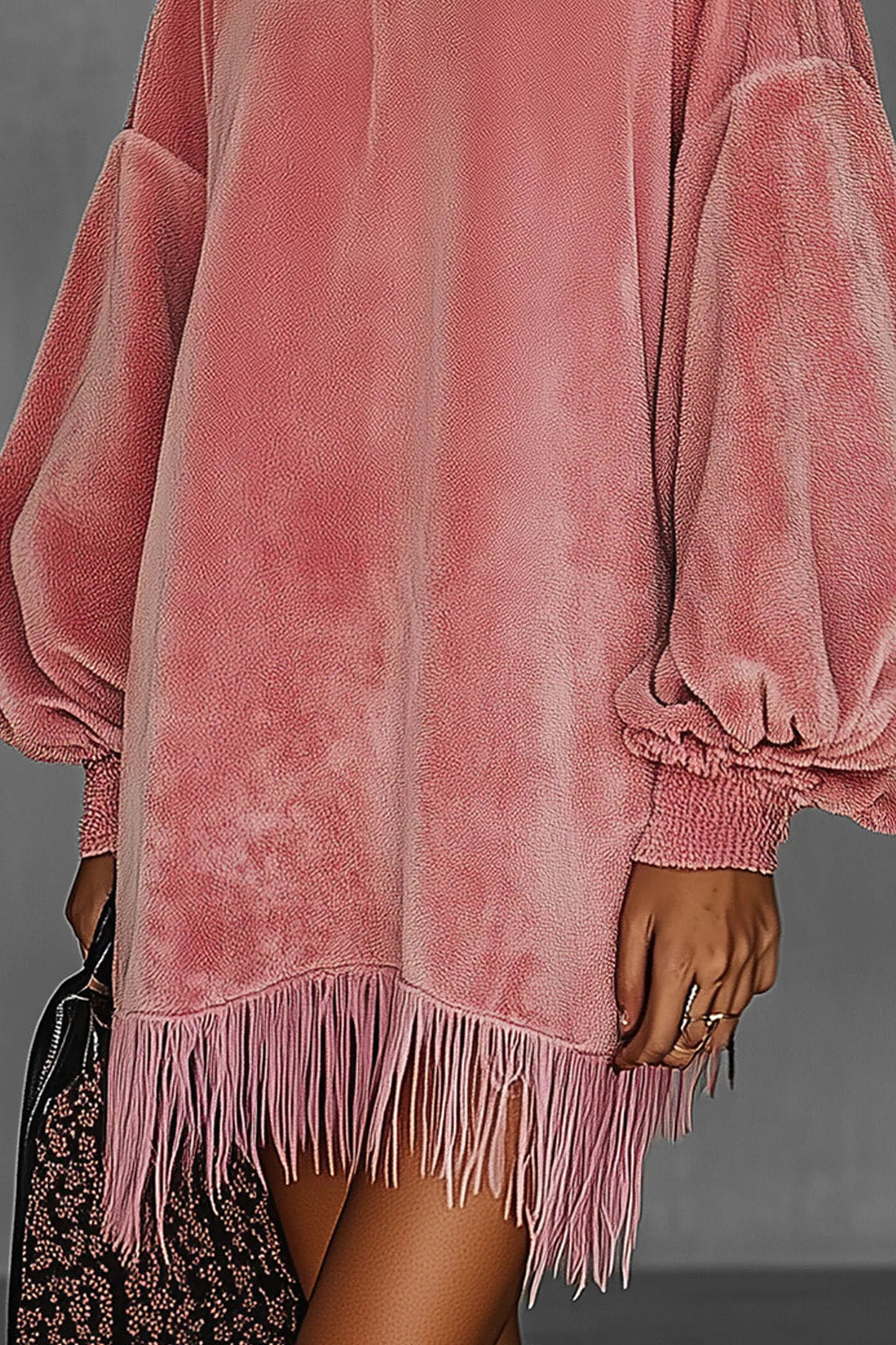 Pink - Model wearing an oversized pink textured mini dress with voluminous balloon sleeves, smocked cuffs, and a long fringed hem.