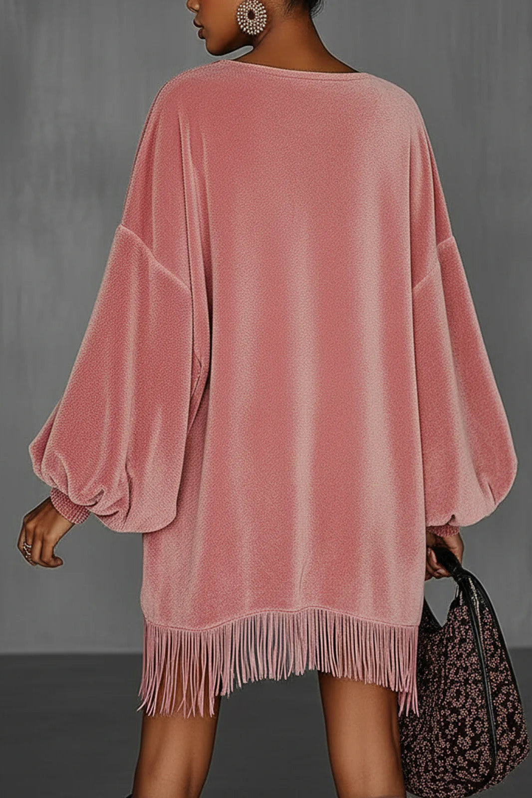 Pink - Model wearing an oversized pink textured mini dress with voluminous balloon sleeves, smocked cuffs, and a long fringed hem.