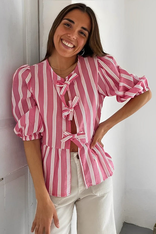 Woman in pink and white striped blouse with bow-tie detail