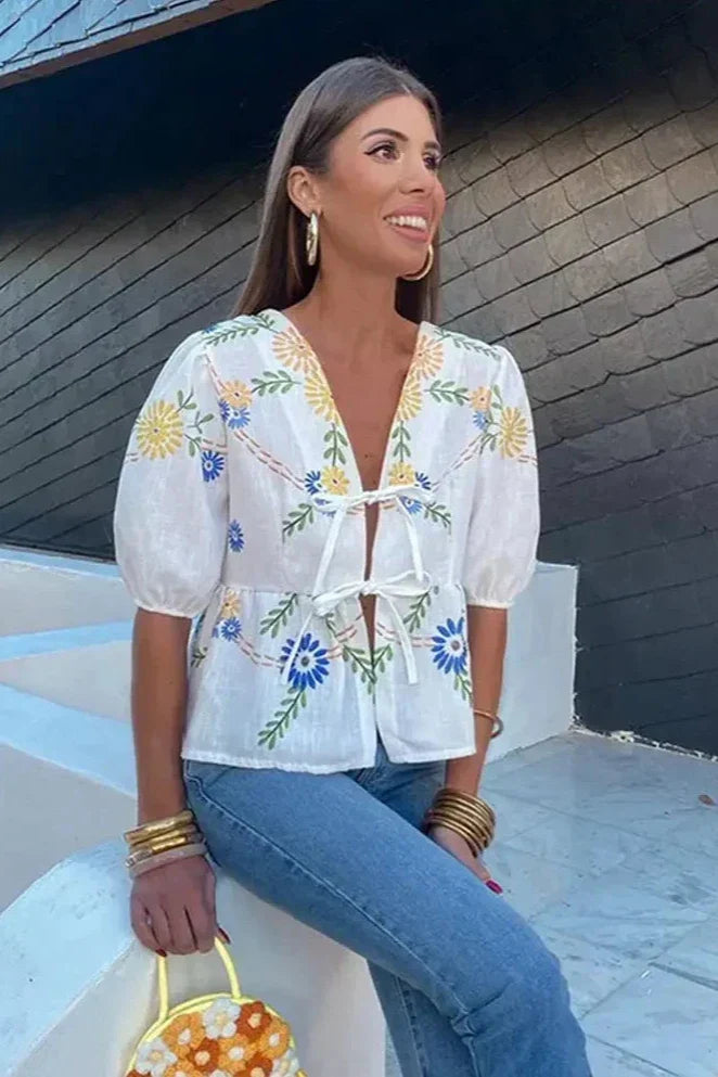 Woman wearing white linen floral embroidered blouse with tie front