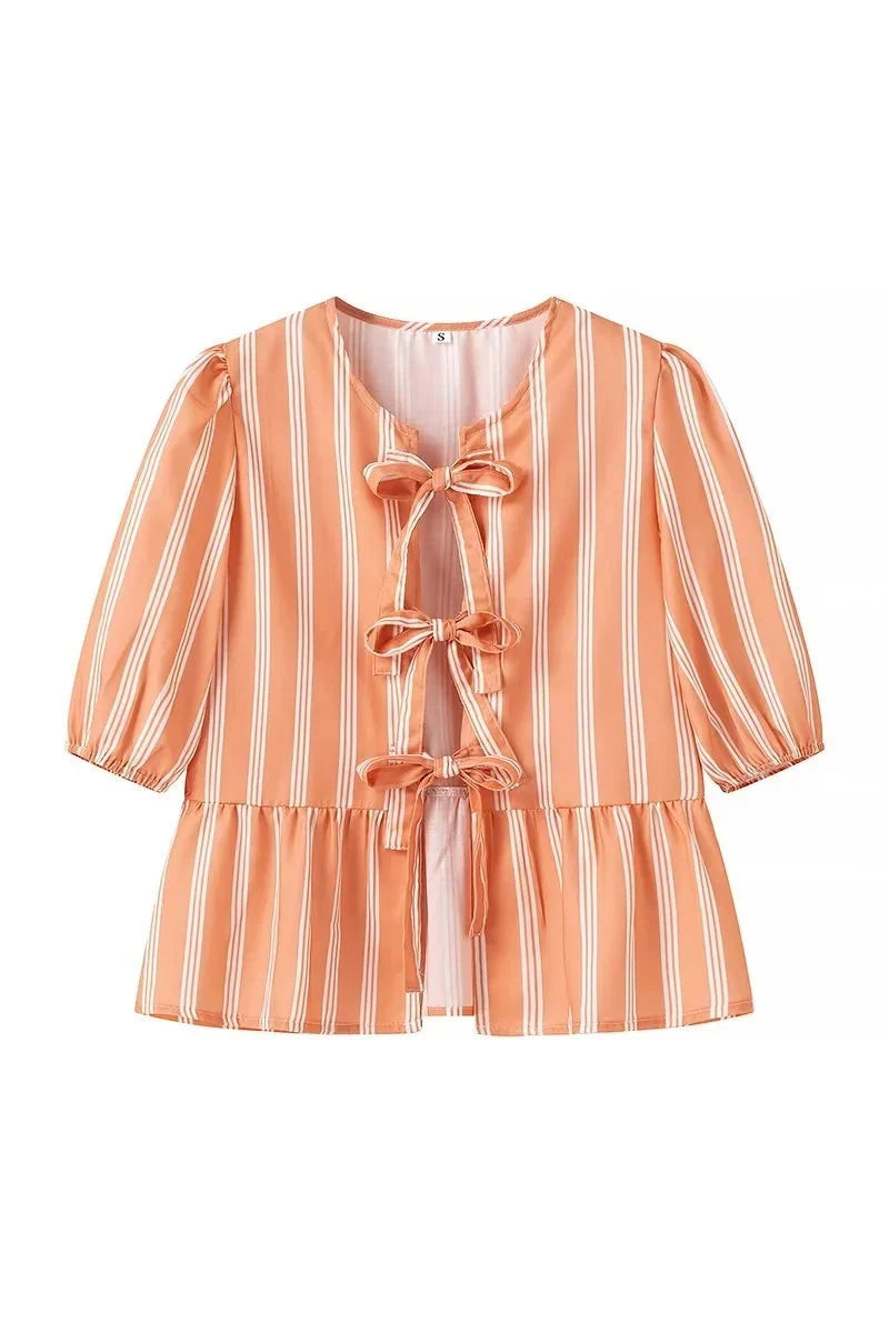 Woman in pink and white striped blouse with bow-tie detail