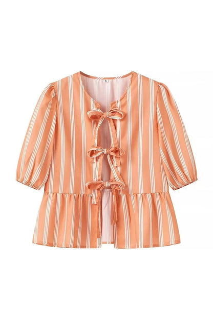 Woman in pink and white striped blouse with bow-tie detail