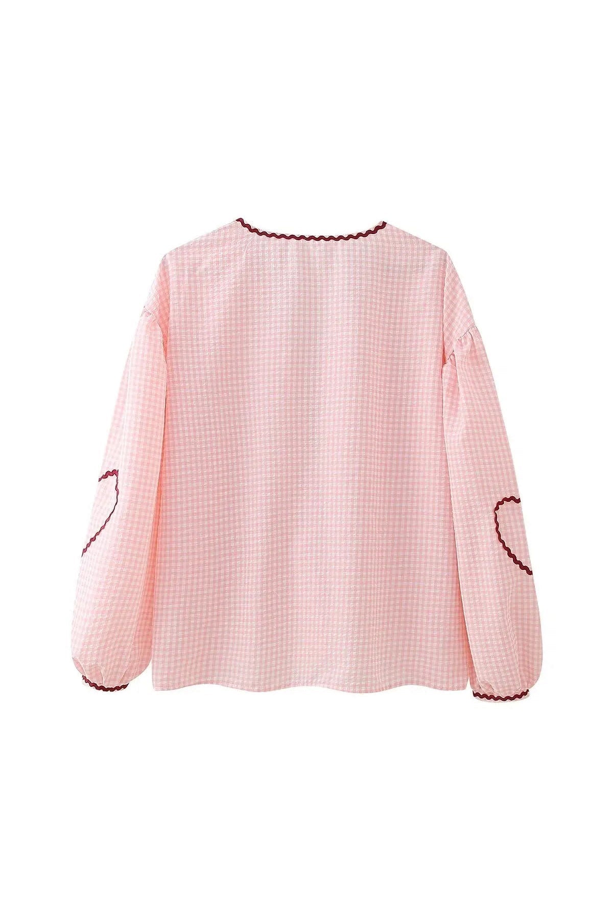 Blue - Women's pink and white gingham tie-front blouse featuring long sleeves, contrast red scalloped trim, and playful heart-shaped appliqués, styled with light wash denim shorts.