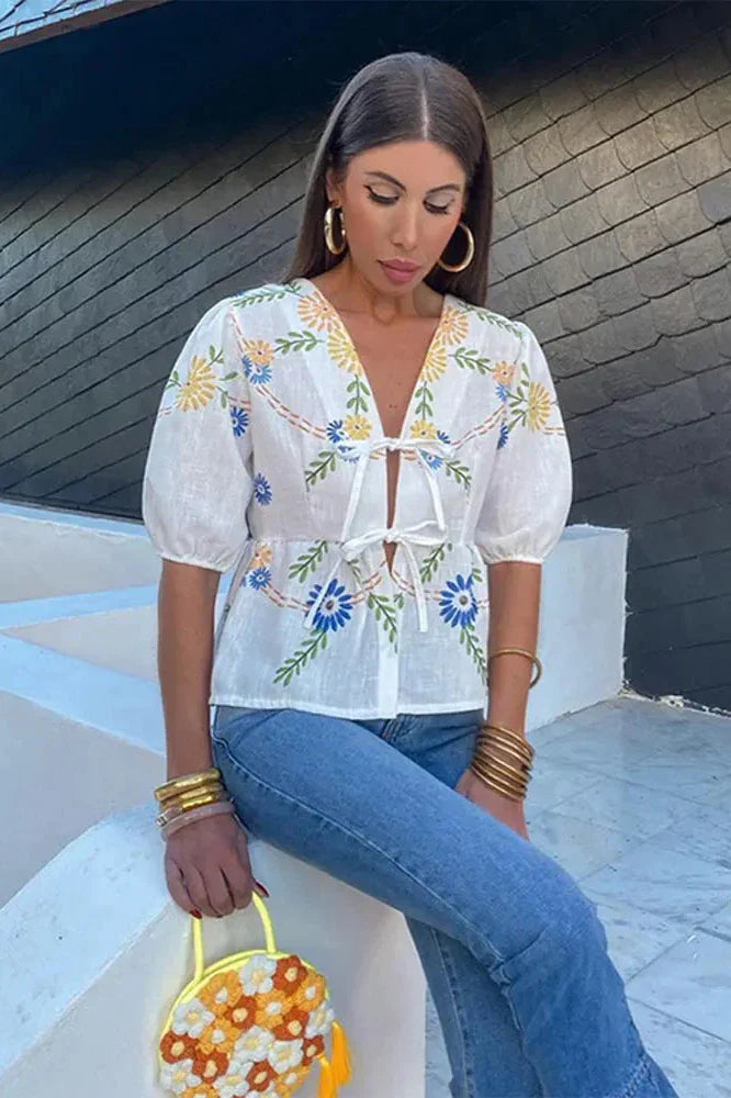 Woman wearing white linen floral embroidered blouse with tie front
