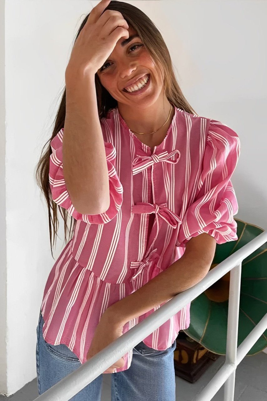 Woman in pink and white striped blouse with bow-tie detail