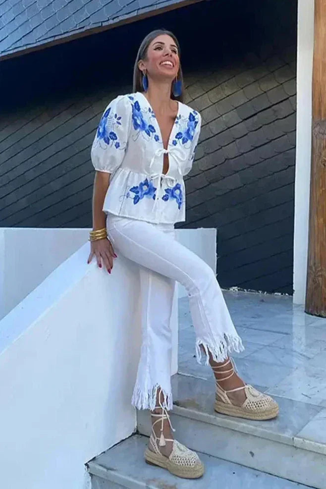 Woman wearing white linen floral embroidered blouse with tie front