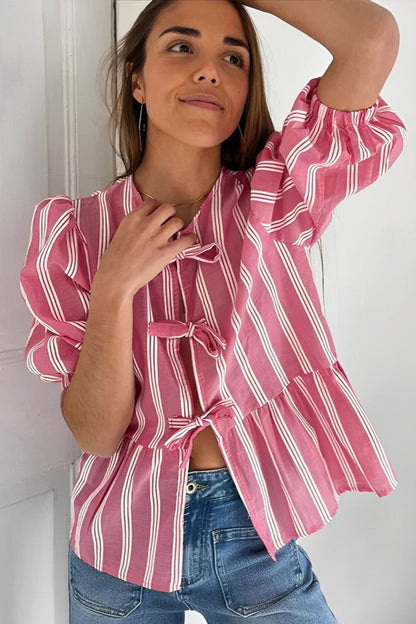 Woman in pink and white striped blouse with bow-tie detail