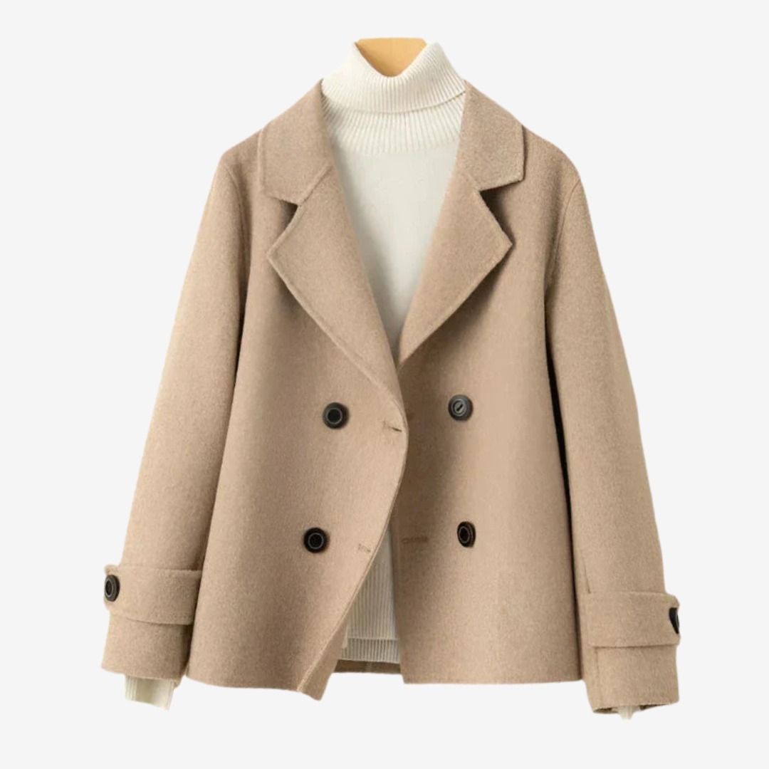 Beige - A woman wearing a camel-coloured, double-breasted cropped jacket with wide lapels and dark buttons, styled over a white turtleneck and blue jeans.