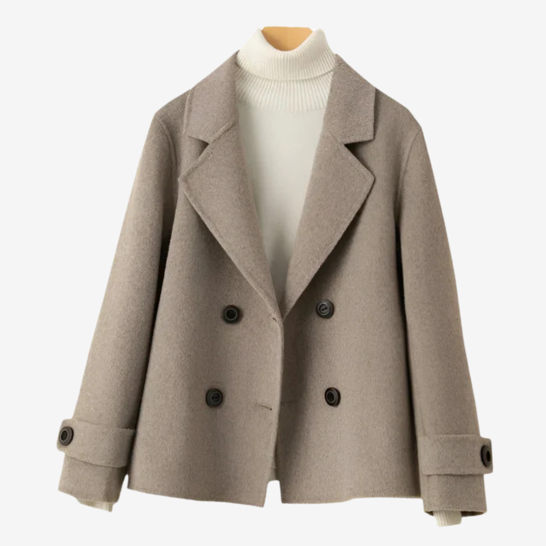Beige - A woman wearing a camel-coloured, double-breasted cropped jacket with wide lapels and dark buttons, styled over a white turtleneck and blue jeans.
