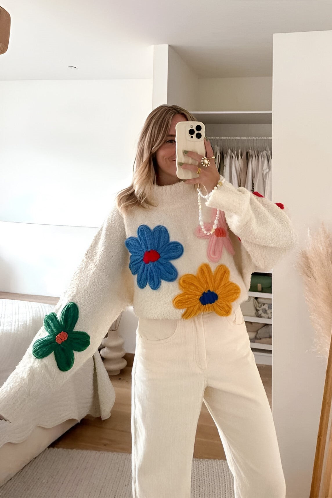 L - Women's fluffy cream mock neck jumper featuring oversized, colourful 3D yarn floral appliqués on the front and sleeves, styled with loose light-wash denim jeans.