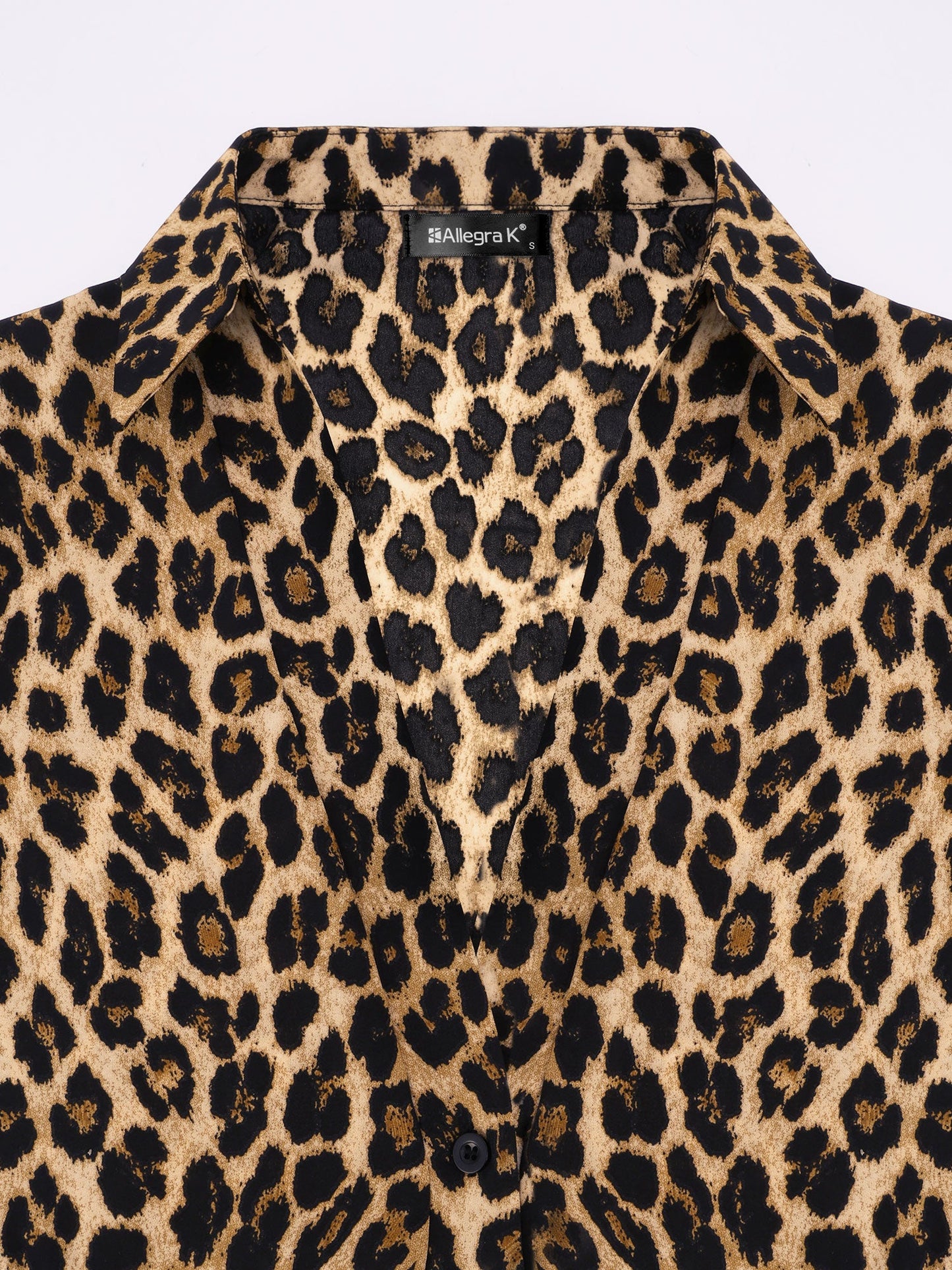 Brown - A woman wearing a long-sleeved, collared, tie-front blouse in a brown and black leopard print, paired with black pants.