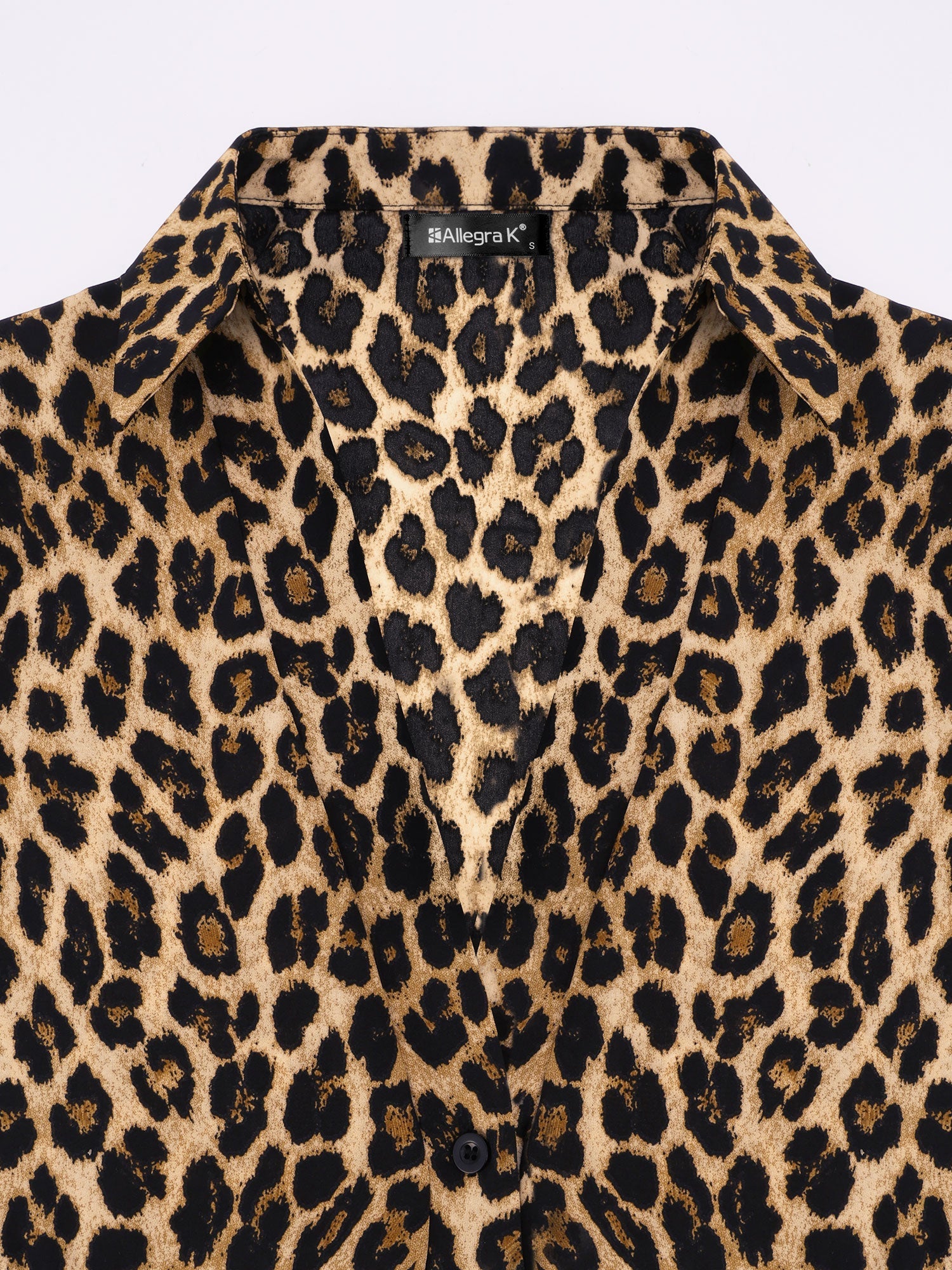 Brown - A woman wearing a long-sleeved, collared, tie-front blouse in a brown and black leopard print, paired with black pants.