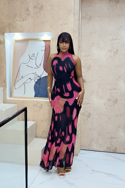 A woman modeling a sleeveless, high-neck maxi dress featuring a bold black, pink, and peach abstract graphic print with a form-fitting silhouette.