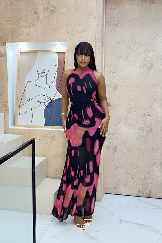 A woman modeling a sleeveless, high-neck maxi dress featuring a bold black, pink, and peach abstract graphic print with a form-fitting silhouette.