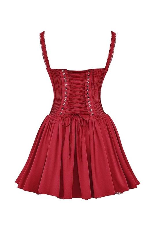 A woman stands in a sunlit vineyard wearing a vibrant red mini dress featuring a structured corset bodice, a ruched sweetheart neckline with a tie-front, wide shirred straps, and a full, flared skirt.
