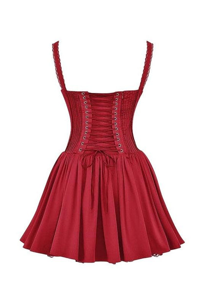 A woman stands in a sunlit vineyard wearing a vibrant red mini dress featuring a structured corset bodice, a ruched sweetheart neckline with a tie-front, wide shirred straps, and a full, flared skirt.