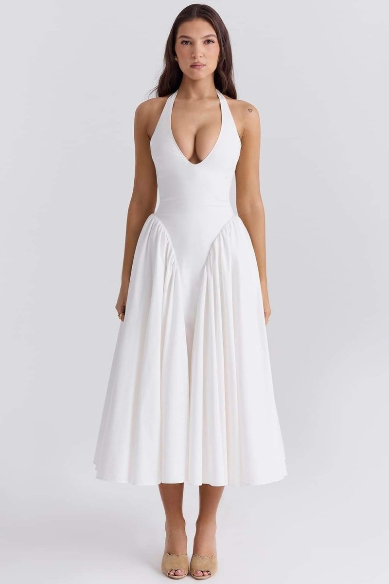 A woman models a white halter midi dress with a plunging neckline and a voluminous full skirt in an outdoor garden setting.