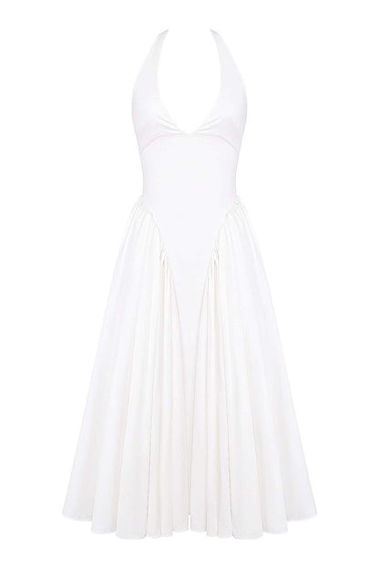 A woman models a white halter midi dress with a plunging neckline and a voluminous full skirt in an outdoor garden setting.