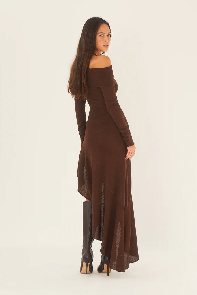 Brown - A woman models a long-sleeved, off-the-shoulder midi dress in a rich chocolate brown. The dress features a form-fitting bodice and a dramatic asymmetrical hemline with cascading ruffles, styled with black high-heeled boots.
