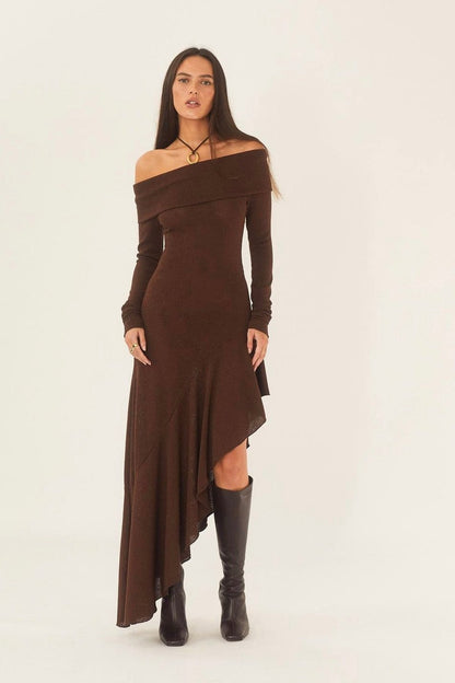 Brown - A woman models a long-sleeved, off-the-shoulder midi dress in a rich chocolate brown. The dress features a form-fitting bodice and a dramatic asymmetrical hemline with cascading ruffles, styled with black high-heeled boots.