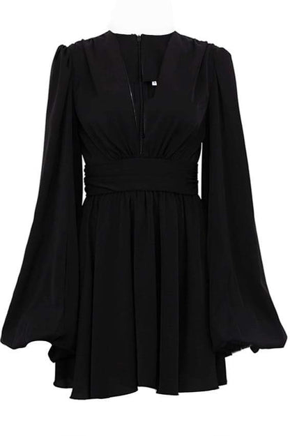 A woman with her hair in a sleek bun models a black mini dress with a plunging V-neckline, extremely voluminous long sleeves, a wide fitted waistband, and a short, flared skirt.