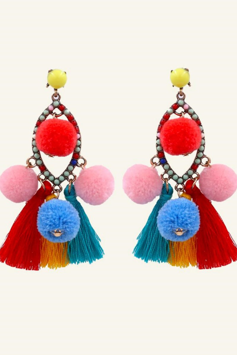 Women's vibrant statement dangle earrings featuring a beaded teardrop frame, colorful red, pink, and blue pom-poms, and sweeping red, yellow, and teal thread tassels.