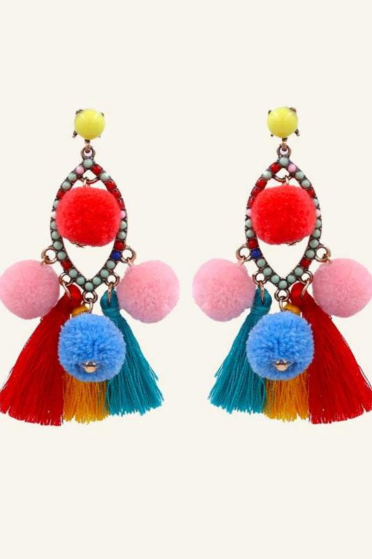 Women's vibrant statement dangle earrings featuring a beaded teardrop frame, colorful red, pink, and blue pom-poms, and sweeping red, yellow, and teal thread tassels.
