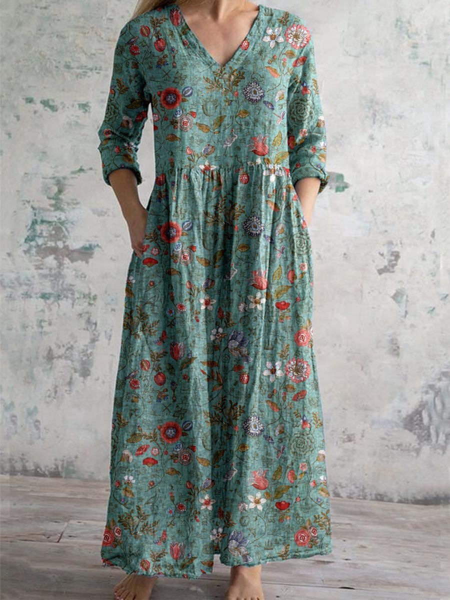 3XL - A woman wearing a teal botanical print linen maxi dress with three-quarter sleeves, a V-neckline, and side pockets, showcasing a relaxed bohemian silhouette.
